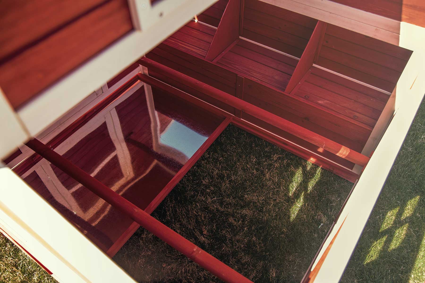 An interior view of the Schoolhouse chicken coop, showing roosting bars, sliding mess pans, and three nesting areas